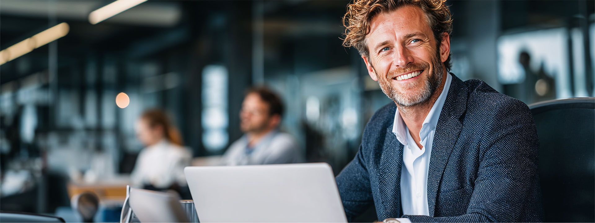 man smiling at desk with laptop